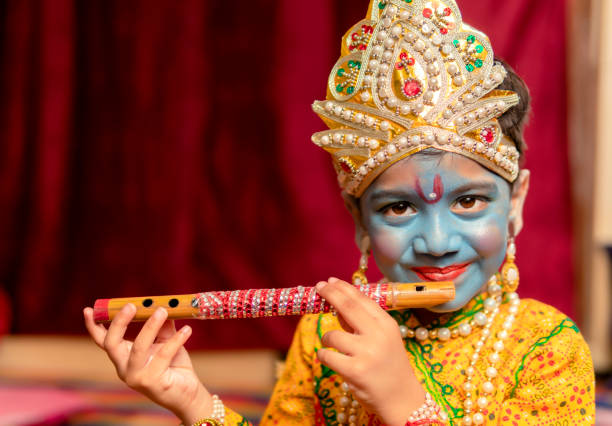 Cute Indian little boy in Lord Krishna dress and playing flute. Happy little Indian boys dressed up as Krishna for the Janmashtami celebration. pictures of krishna stock pictures, royalty-free photos & images