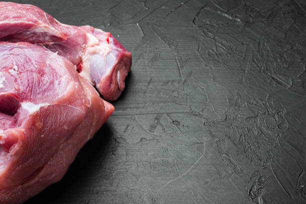 istock Raw meat, piece of pork, on black dark stone table background, with copy space for text 1414955883