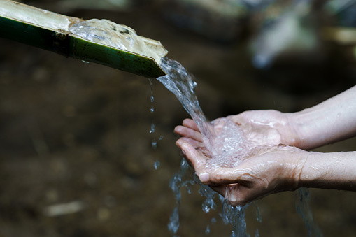 Hands with fresh, cold, potable source water on a mountain, Drinking Spring, Wooden Pipe of Fresh Potable, Unpolluted, Natural Spring Water. world water day and water save concept