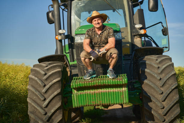 istock Farmer with tractor in canola field 1414958835