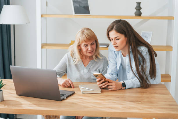 istock Learning how to use modern technologies. Smartphone and laptop. Mother and daughter is together at home 1414960502