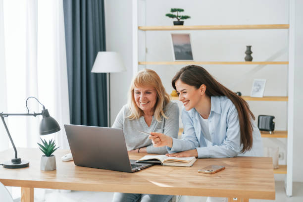 istock Learning how to use modern technologies. Smartphone and laptop. Mother and daughter is together at home 1414960542