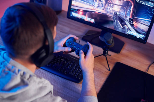 istock Using the joystick. Online streamer playing FPS shooter game at home 1414962157