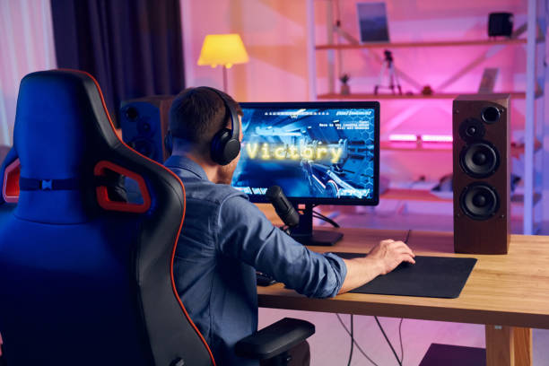 istock View from behind. Online streamer playing FPS shooter game at home 1414962255