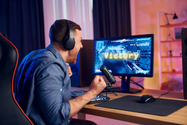 istock Man wins this game. Online streamer playing FPS shooter at home 1414962278