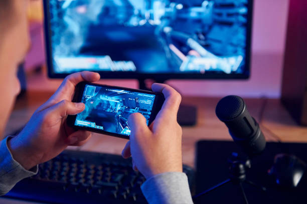 istock Using the smartphone. Online streamer playing FPS shooter game at home 1414962651