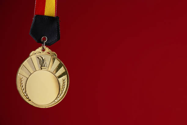 gold color medal against red background with copy space