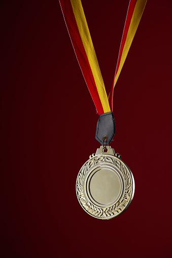 gold color medal against red background with copy space