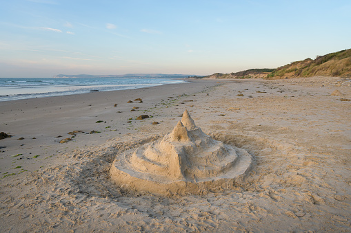 Stock photo showing close-up view of a complex sandcastle built on a sunny, golden sandy beach. Summer holiday, tourism and activities concept.