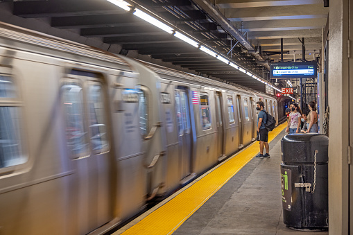 New York City, USA - July 30, 2018: Train car in motion with its driver looking and people around in a subway station of New York City, USA