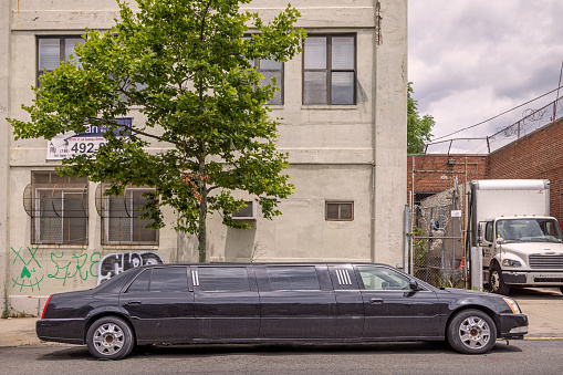 Brooklyn, New York, NY, USA - July 6th 2022: Black stretched limousine in front of factory building