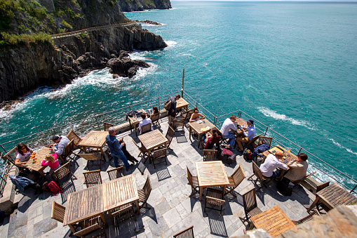 Riomaggiore, Cinque Terre - Italy, May 12, 2019: Outdoor restaurant on observation deck with sea view, Riviera di Levante, people sitting at tables
