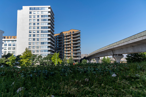 Modern residential buildings next to a viaduct surrounded by greenery.