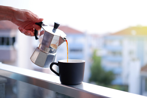 drinking moka pot coffee on the balcony at sunrise, italian culture coffee