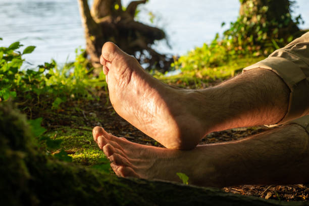 middle-aged man with pain in the soles of his feet, flat feet, joint problems middle-aged man walking in the woods with pain in the soles of his feet, flat feet, joint problems and mobility problems. pes planus stock pictures, royalty-free photos & images