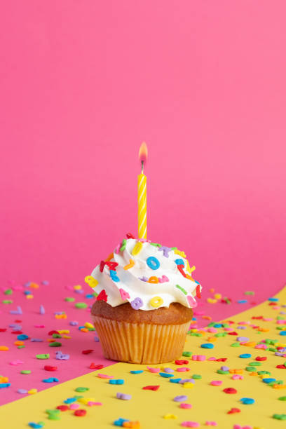 istock Cupcake on a pink-yellow background with candles. 1414968773