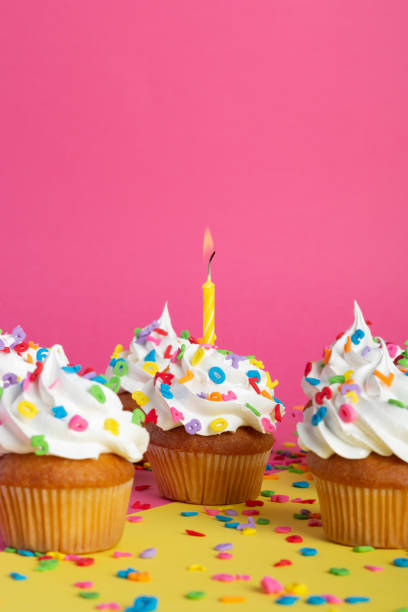 istock Cupcakes on a pink-yellow background with candles. 1414968789
