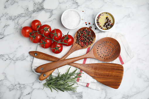 Flat lay composition with cooking utensils and fresh ingredients on white marble table