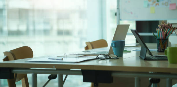 istock Modern office with laptop computer, coffee cup, financial document and potted plant on black wooden table. 1414969630