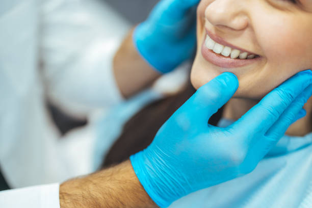 klientin lächelt, während ein zahnarzt sie in einer zahnklinik untersucht - kieferorthopäde stock-fotos und bilder