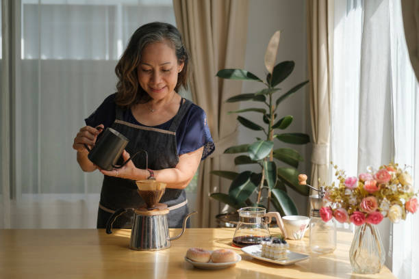 istock Happy middle aged woman preparing coffee for breakfast in comfortable home kitchen. Retirement, Healthy seniors lifestyle. 1414970215
