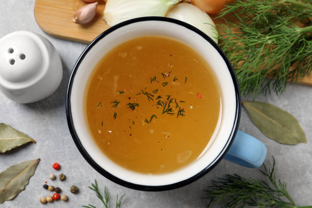 istock Hot delicious bouillon in cup and ingredients on light grey table, flat lay 1414970975