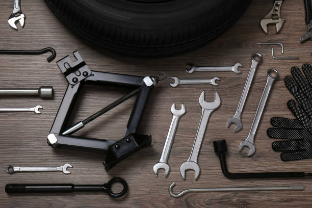 istock Car wheel, scissor jack, gloves and different tools on wooden surface, flat lay 1414971467