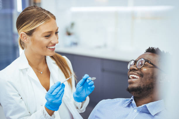 istock Smiling young man sitting in dentist chair while doctor examining his teeth. 1414971633