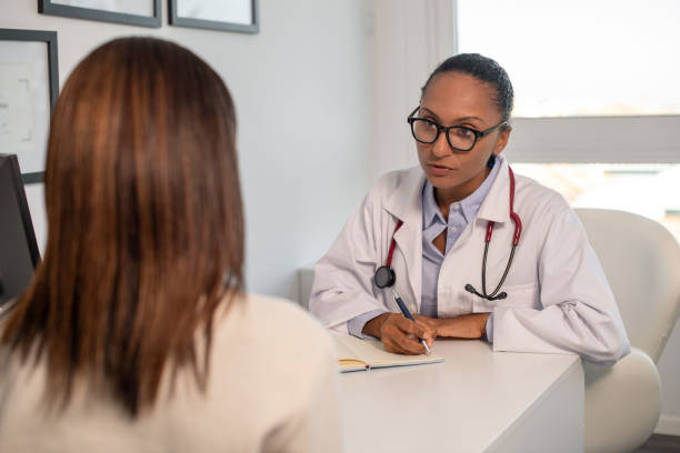 istock Confident doctor writing symptoms of female patient in notebook 1414971902