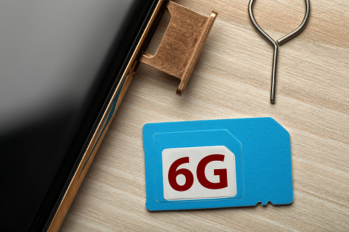 6G technology, Internet concept. SIM card with smartphone on wooden table, closeup