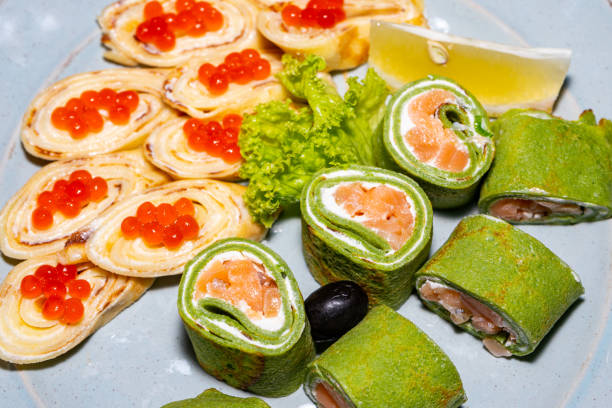 Some green sushi with red fish and pancakes with red caviar close-up stock photo