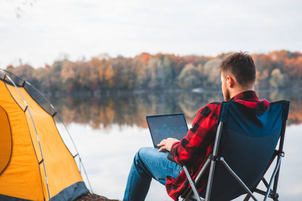 homme assis sur une chaise près du lac d’automne - leaving business landscape men photos et images de collection