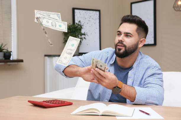 istock Young man throwing money at table indoors 1414974488