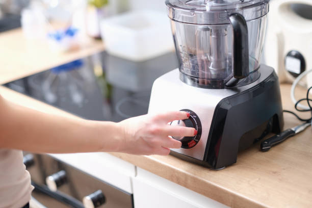 istock Woman switches button on electric blender in kitchen 1414974667