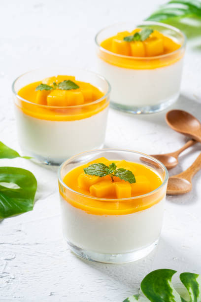 istock Delicious double colored mango panna cotta mousse pudding on white table background. 1414974707