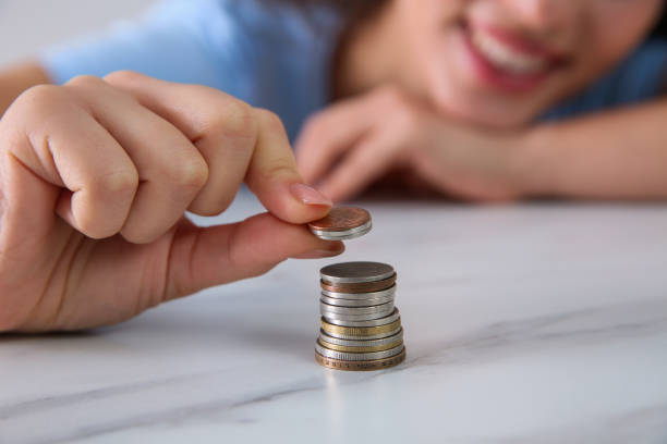 istock Young woman stacking coins at table, focus on hand. Money savings 1414974974