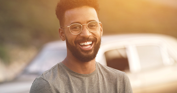 Happy, carefree and excited young man on a roadtrip alone, on a journey of self discovery and freedom. Face portrait of a smiling guy feeling positive, traveling and enjoying life with flare