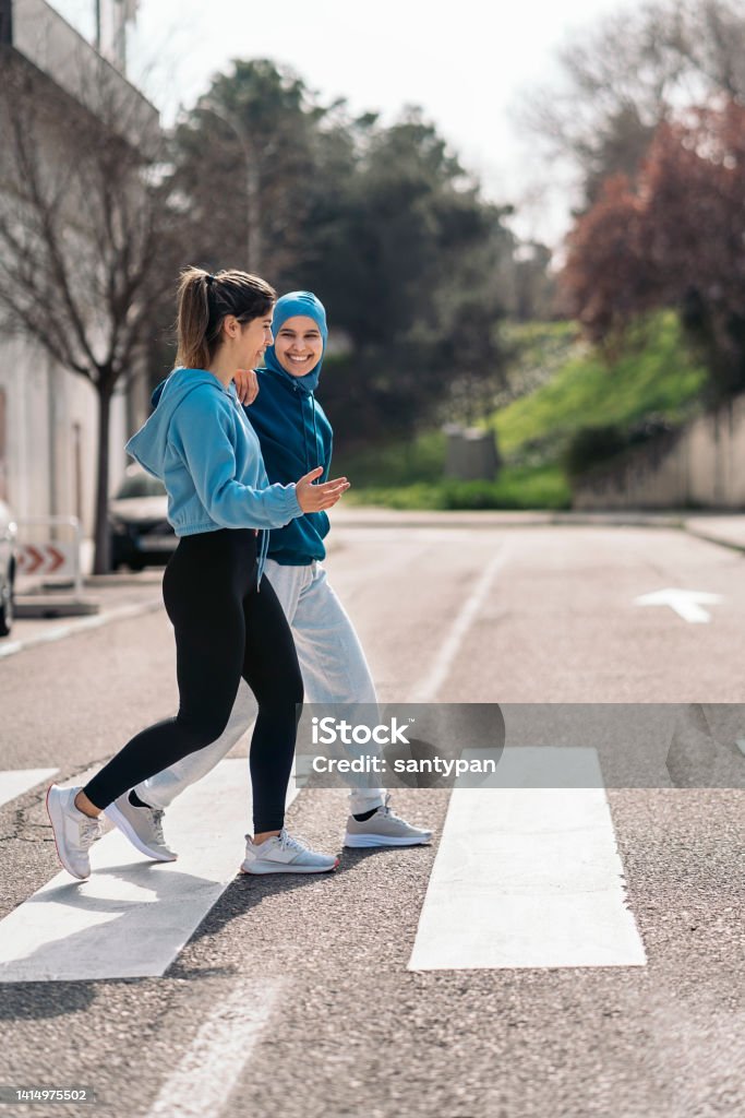 Runners  in zebra Crossing Cheerful active girls wearing sports clothes running and crossing the street. Walking Stock Photo