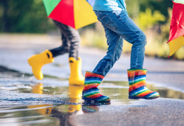istock Children jumping in the puddle in rubber boots 1414975520