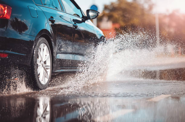 Car driving through the puddle and splashing by water. stock photo