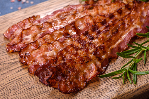 Delicious roasted ham with slices on a wooden cutting board with spices and herbs. Making a hearty breakfast