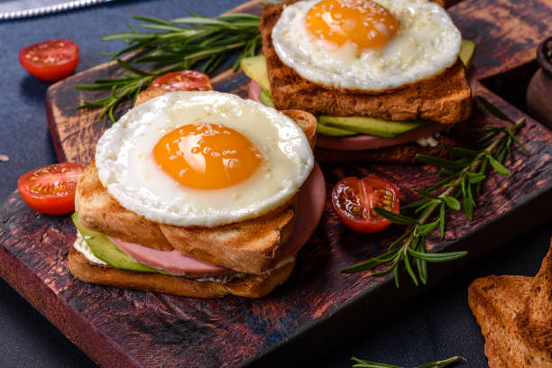 istock Fresh, delicious sandwiches with fried egg, ham, butter, avocado and sesame seeds 1414977838