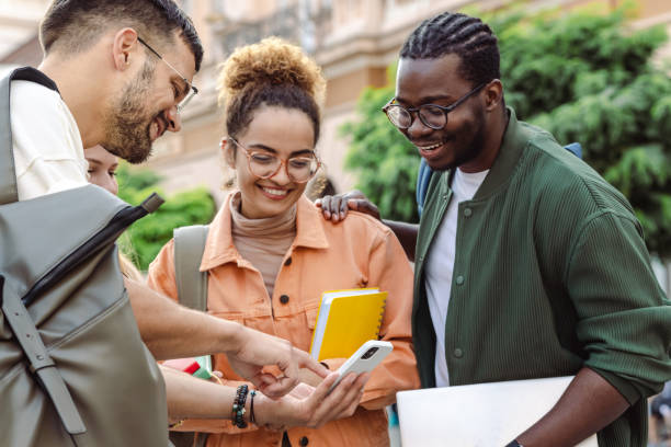 istock Cheerful students using smart phone on the street 1414980086