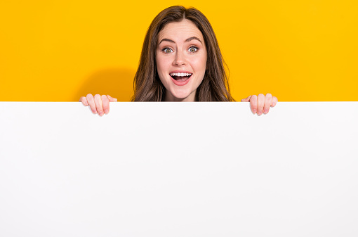 Photo of funky astonished person hide behind empty space blank open mouth isolated on yellow color background.