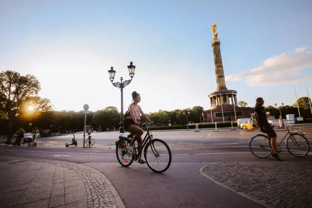 Commuter or a tourist woman on the bicycle in Berlin district of Kreuzberg, on a bright and sunny summertime day, riding through the traffic.