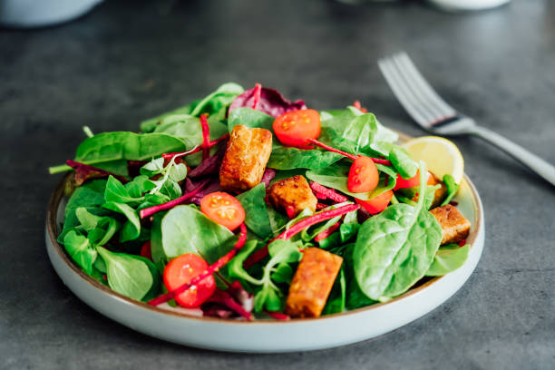 istock Healthy salad with roasted tempeh, fresh cherry tomatos, beetroot straws, spinash and lettuce leaves on plate. Tempeh is fermented soy bean. Plant based protein. Healthy Cooking and eating. Go vegan 1414981329