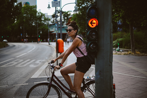 Woman riding her bicycle in Berlin, Germany. She is standing on the traffic light, going to work or just sightseeing.