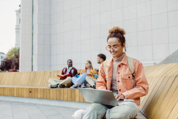 istock Young female student using laptop on the bench on campus 1414982481