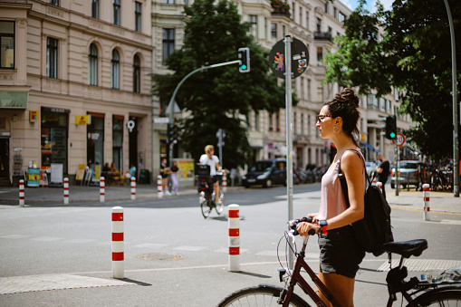 Commuter or a tourist woman on the bicycle in Berlin district of Kreuzberg, on a bright and sunny summertime day.