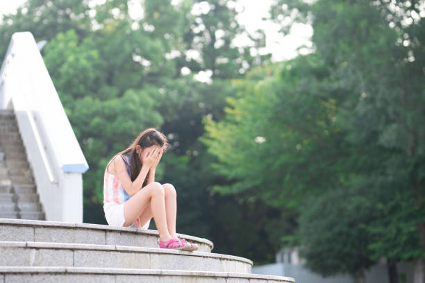 istock girl sitting on stairs and crying 1414985821